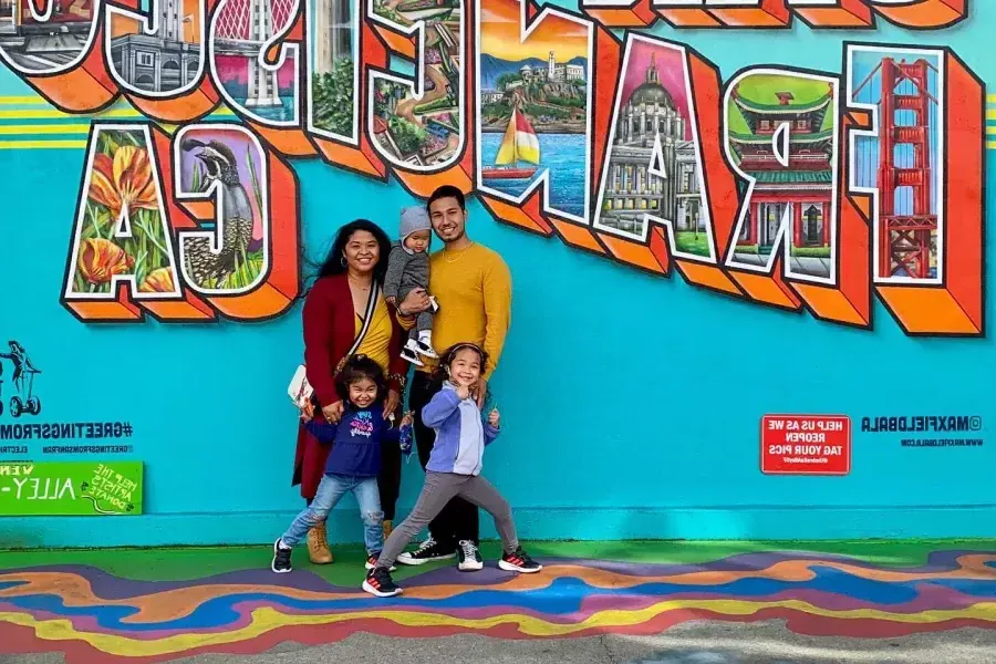 Eine Familie posiert für ein Foto vor einem Wandgemälde in San Francisco